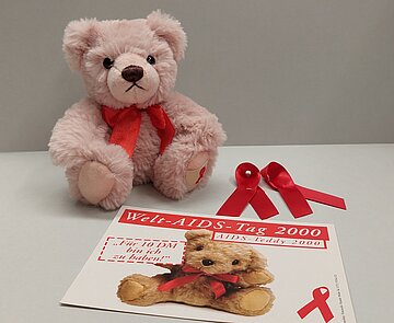 Postkarte und Teddybär der AIDS-Hilfe Karlsruhe e.V. zum Welt-AIDS-Tag
