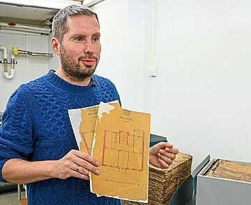 Begeistert sich für Originalquellen: Diplom-Archivar Eric Wychlacz mit restaurierten Plänen im Stadtarchiv.