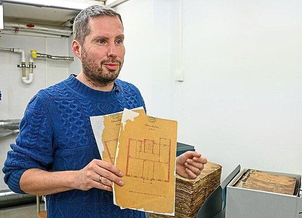 Begeistert sich für Originalquellen: Diplom-Archivar Eric Wychlacz mit restaurierten Plänen im Stadtarchiv.