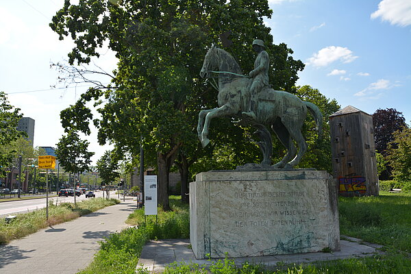 Das Leibdragoner-Denkmal vor der Christuskirche beim Mühlburger Tor mit der kommentierenden Informationsstele im Hintergrund, 2023