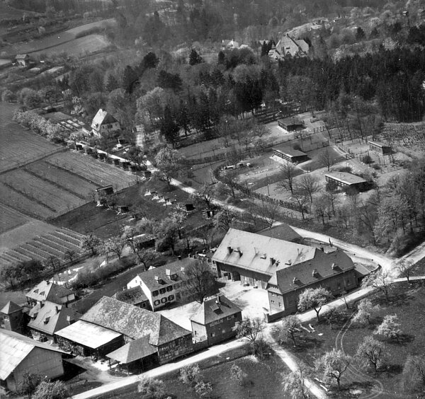 Die Luftaufnahme des Rittnerthofs von 1958 zeigt die Hofanlage und rechts davon die Hühnerfarm. Rechts am oberen Bildrand ist das Dach der Villa Merton erkennbar, das Haus links ist das Gärtnerhaus
