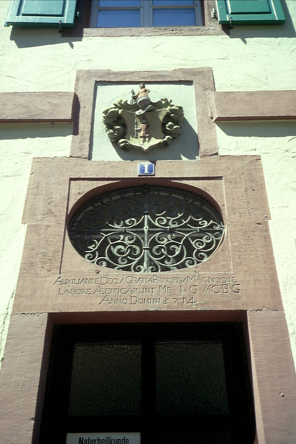 Text der lateinischen Inschrift auf dem Türsturz des Hauses Jägerstraße 1 in Durlach: AUXILIANTE DEO / GRATIA PRINCIPIS / MAGNOQUE LABORE AEDIFICARUNT ME I G & C B G ANNO DOMINI 1714