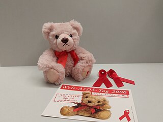 Postkarte und Teddybär der AIDS-Hilfe Karlsruhe e.V. zum Welt-AIDS-Tag